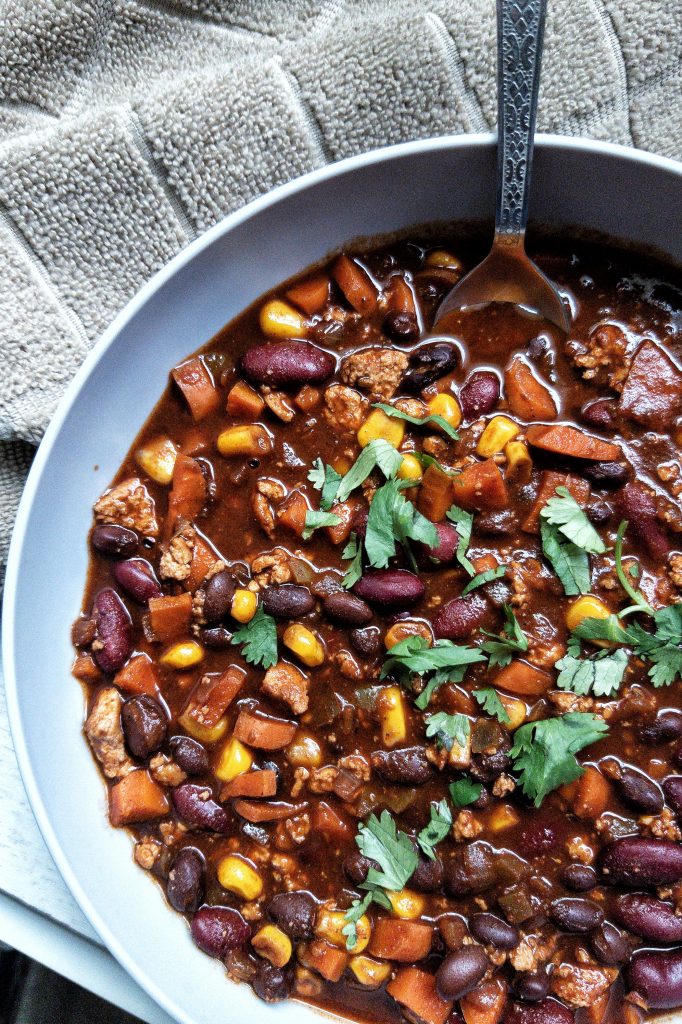 Bowl of vegetable chili with a brown serving towel.