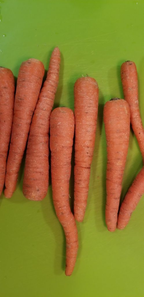 Whole carrots on a green chopping board