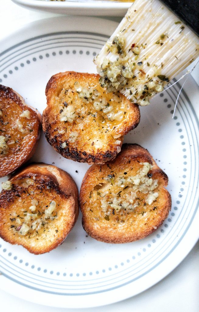 Vegan garlic butter dipping sauce brushed onto toasted bread