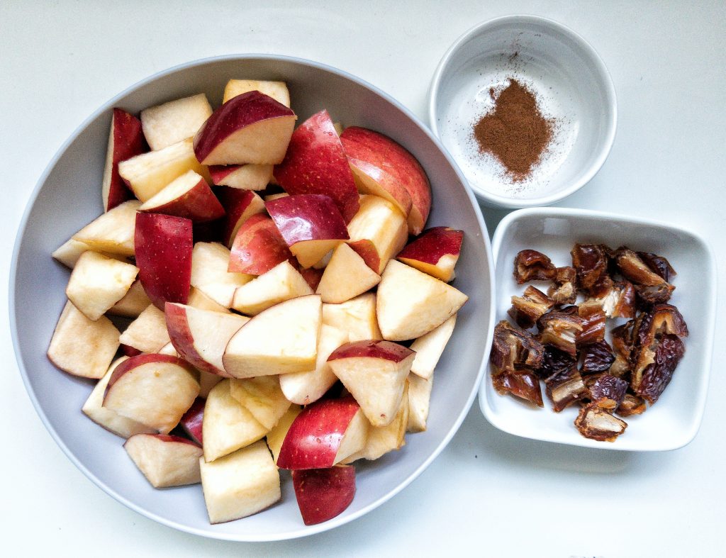 Chopped apples in a bowl with a side of dates and ground cinnamon