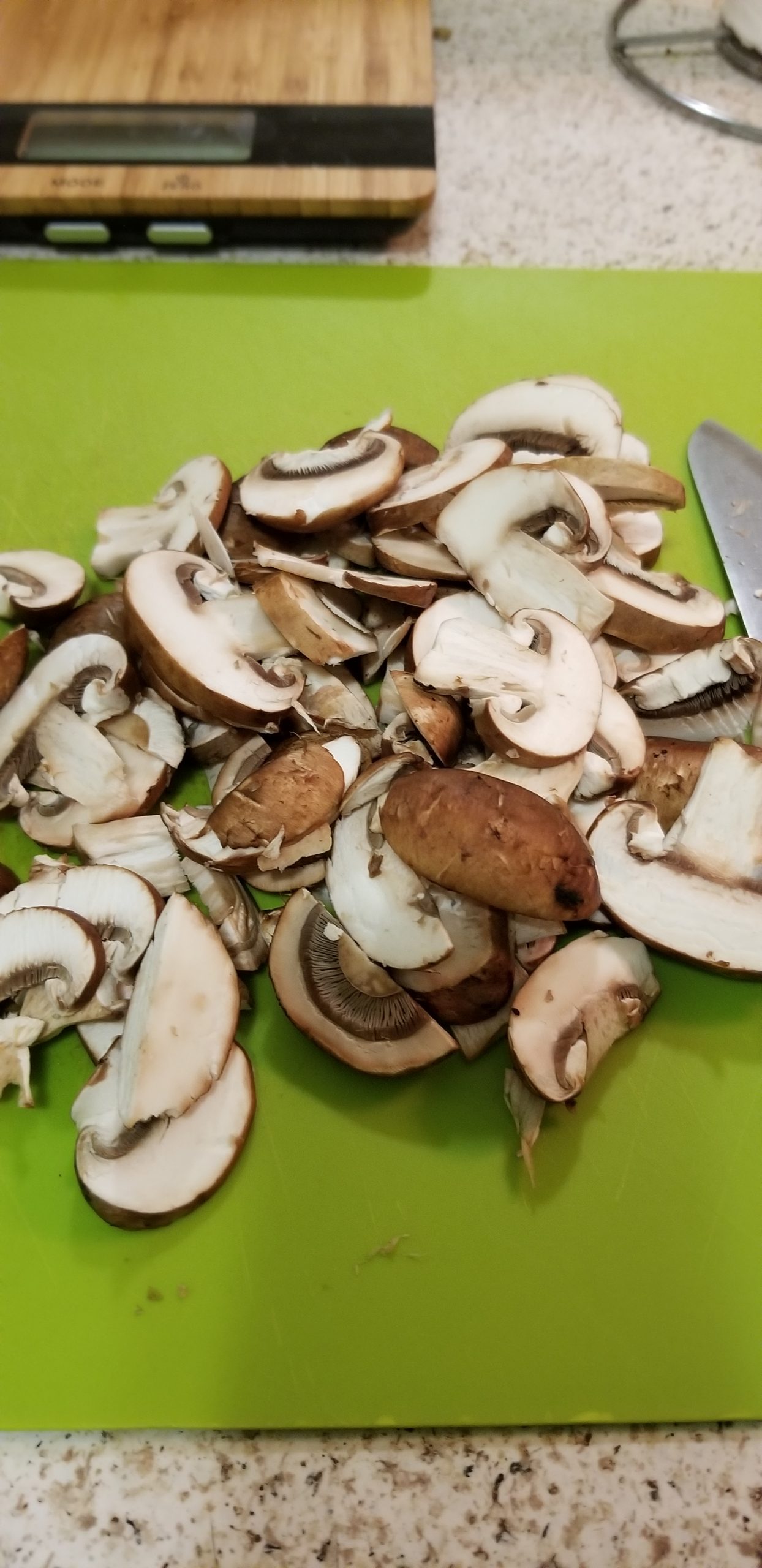 Sliced mushrooms on a green chopping board 