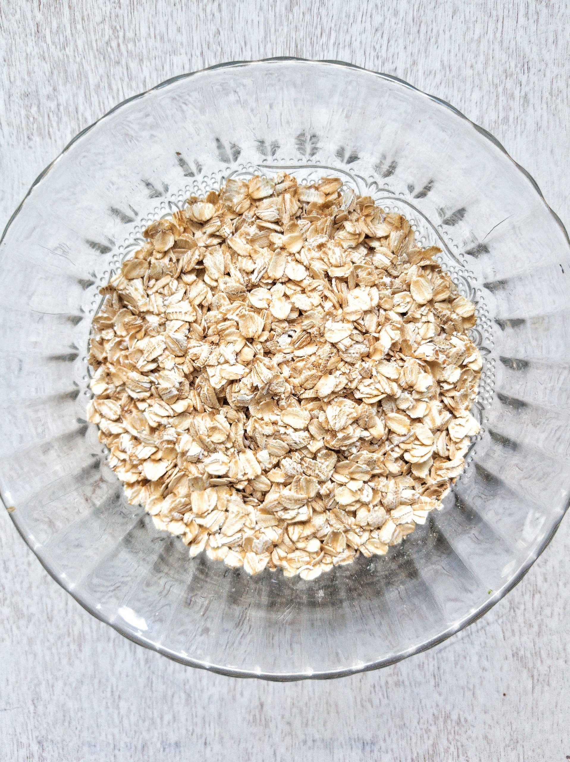 Rolled oats or old-fashioned oats in a clear, glass bowl. 