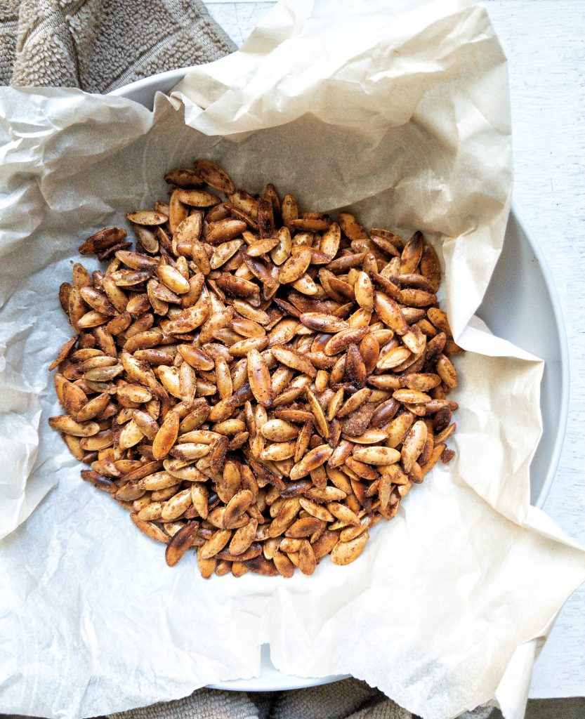 Toasted cinnamon brown sugar pumpkin seeds in a bowl lined with parchment paper