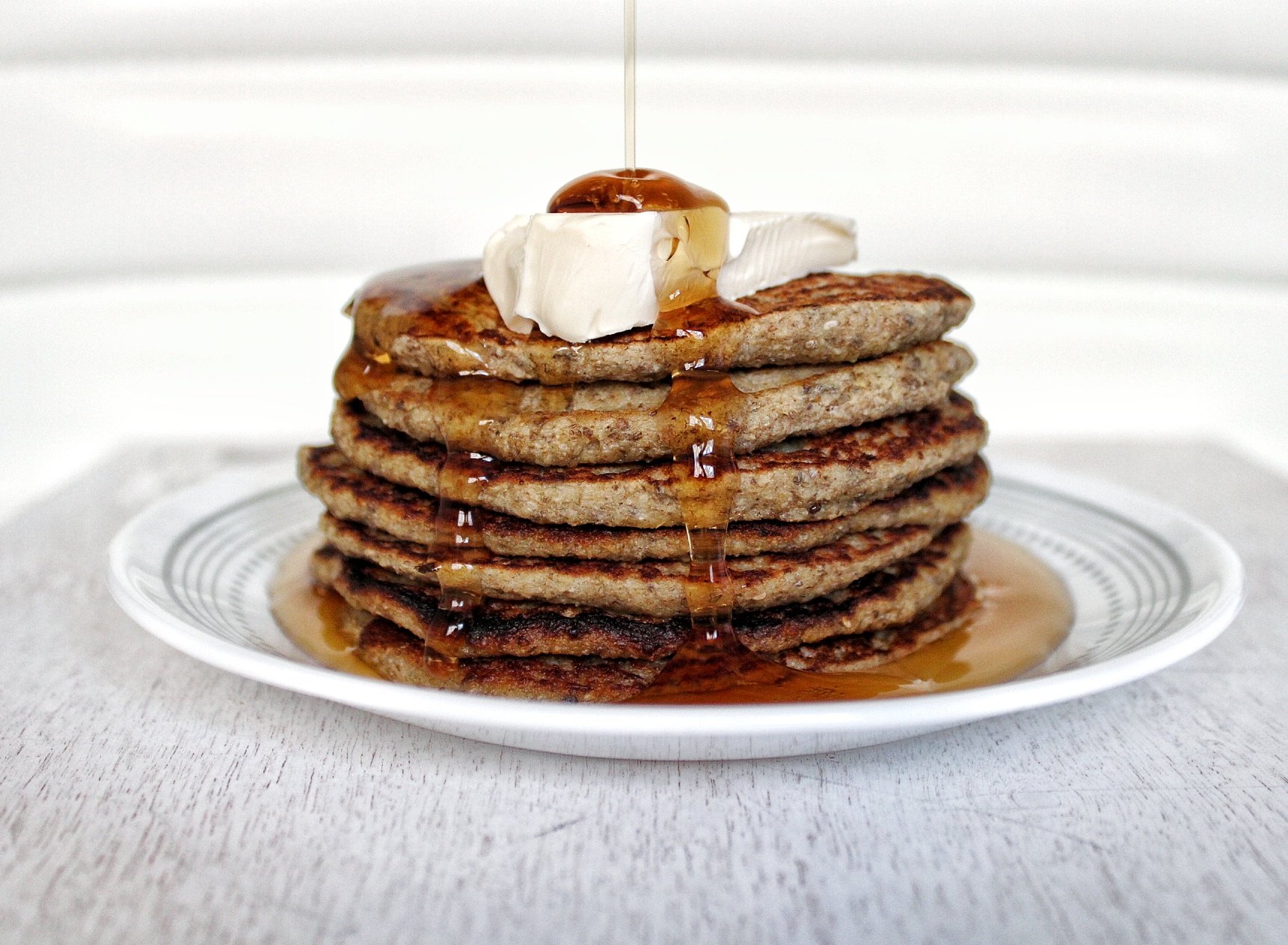 Stack of gluten-free, vegan banana pancakes with a drizzle of syrup and vegan butter