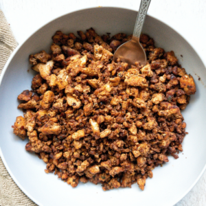 Pan fried tofu sausage pieces in a gray bowl with a silver spoon