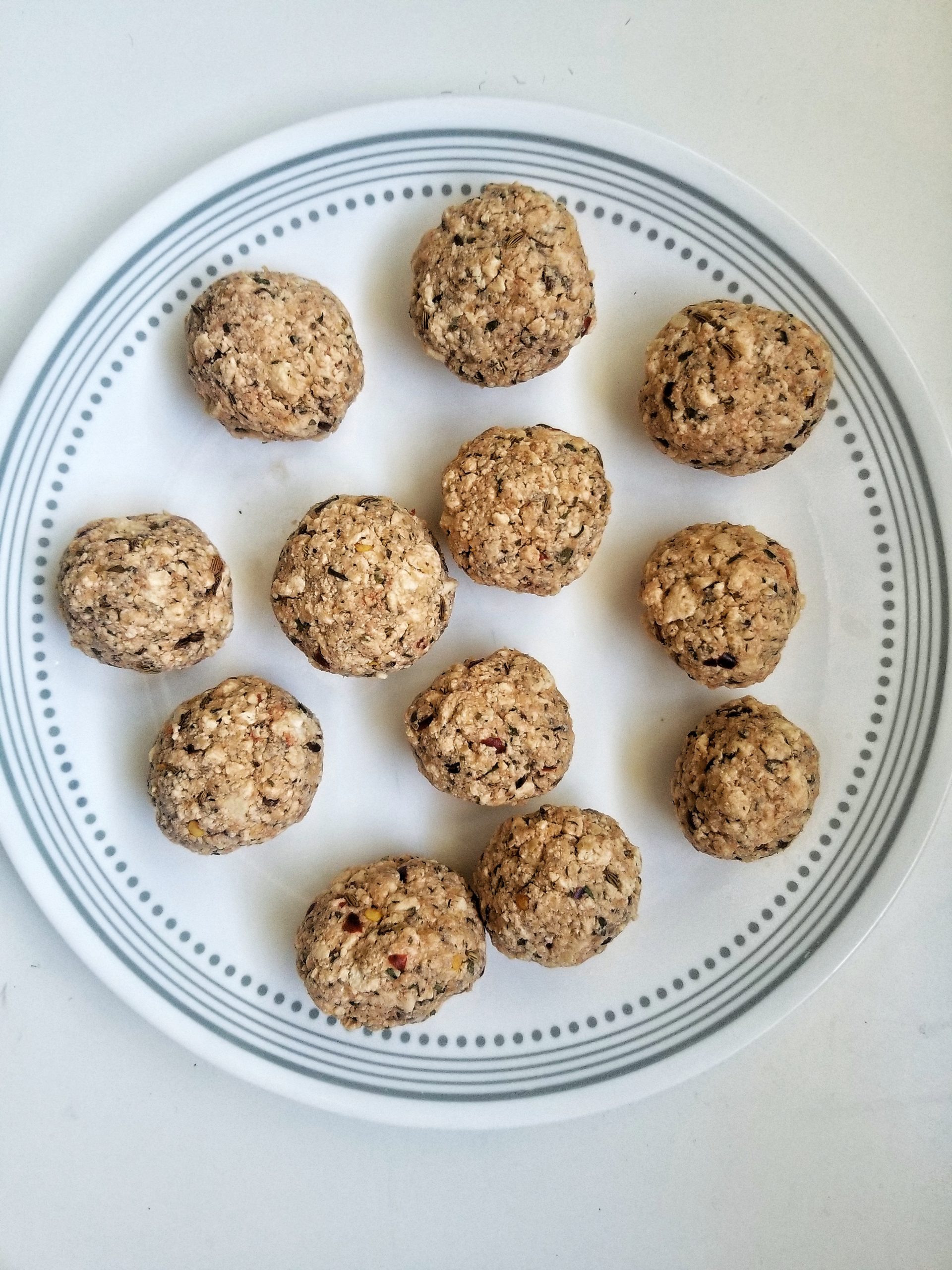 Uncooked, vegan tofu meatballs on a white plate 