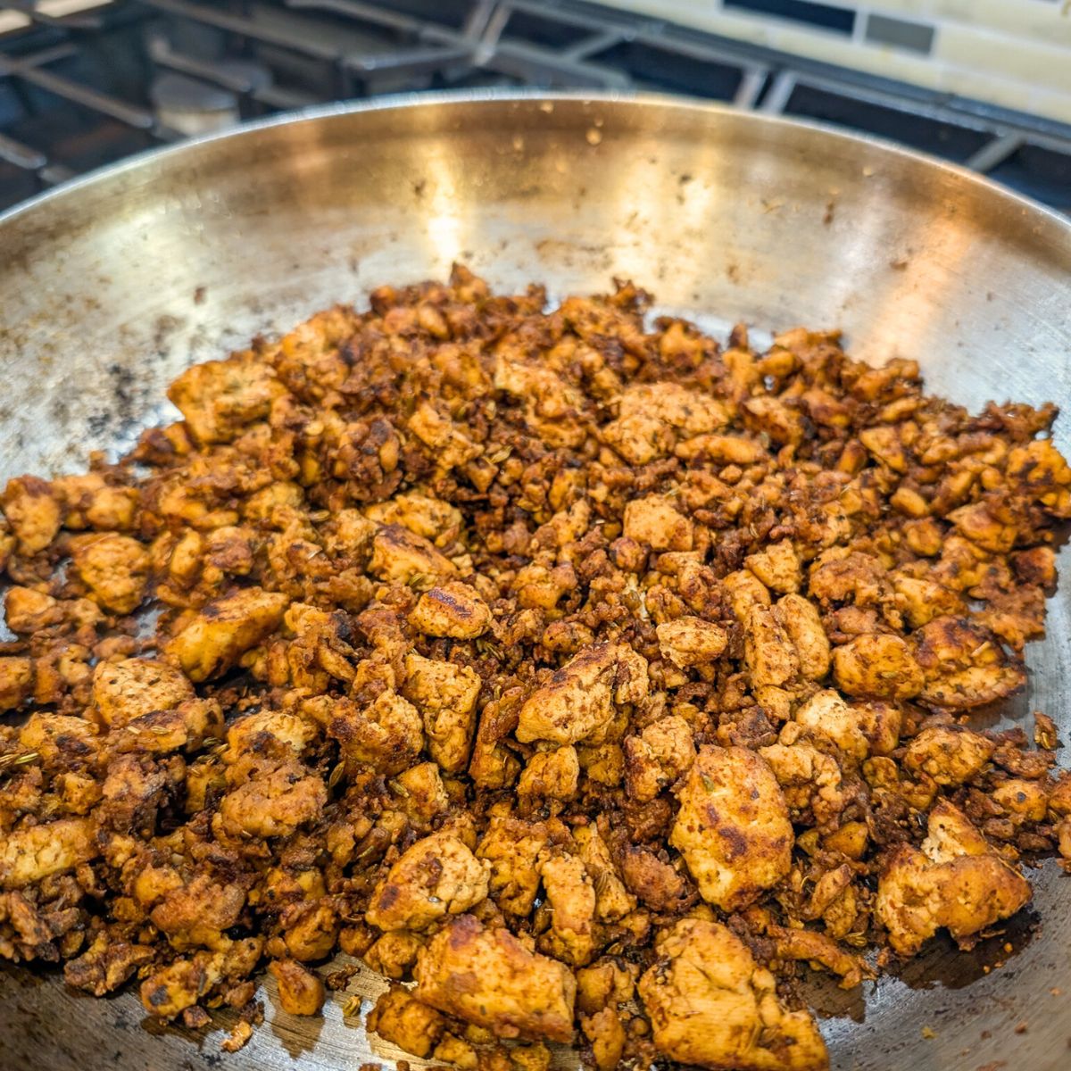 Vegan sausage crumbles made from tofu, cooking over high head in a cast iron skillet.