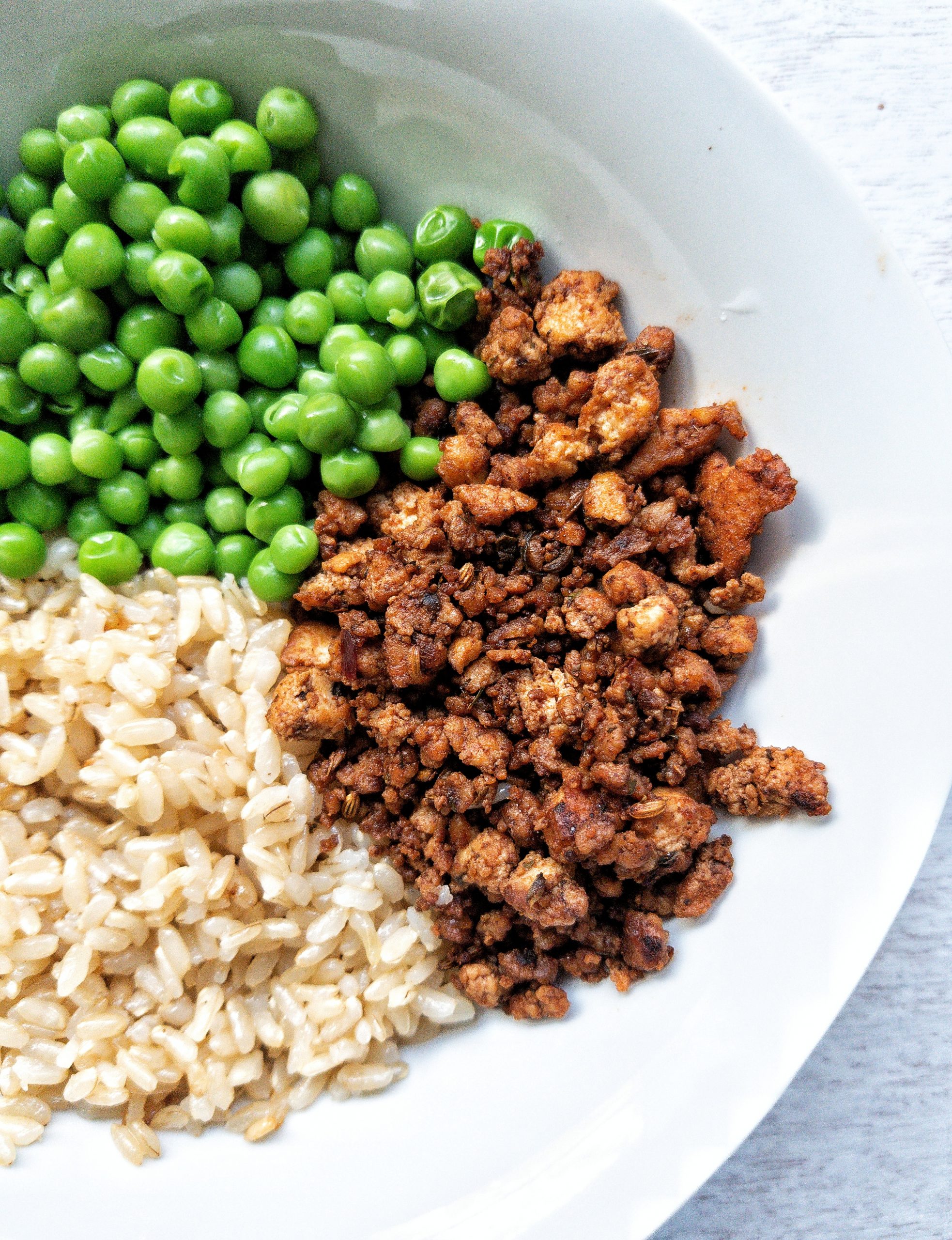 Bowl with a side of tofu sausage crumble, green peas, and brown rice 