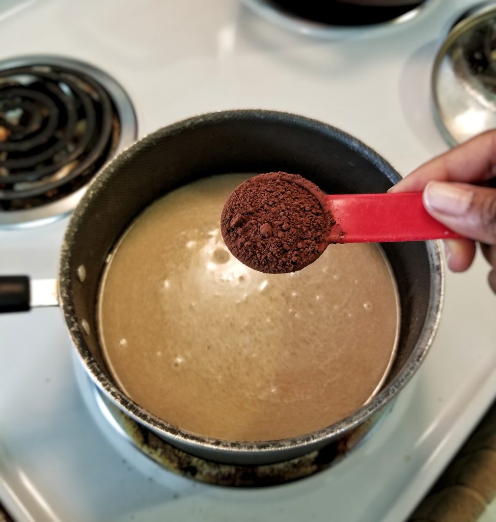 Saucepan over medium heat with a closeup of one tablespoon of dutch-process cocoa powder