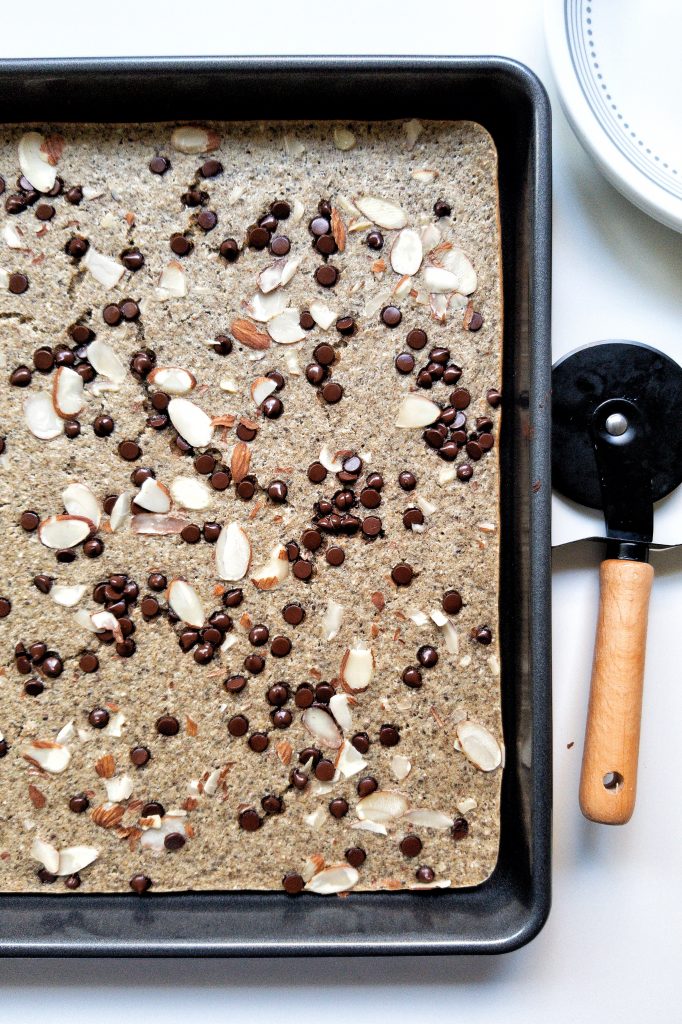 Baked sheet pan pancakes topped with chocolate chips and sliced almonds.