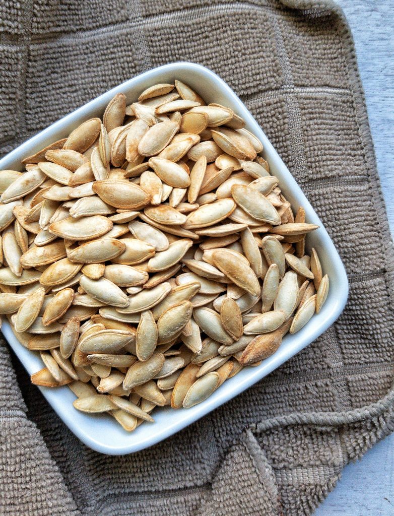 Raw pumpkin seeds in a small white bowl