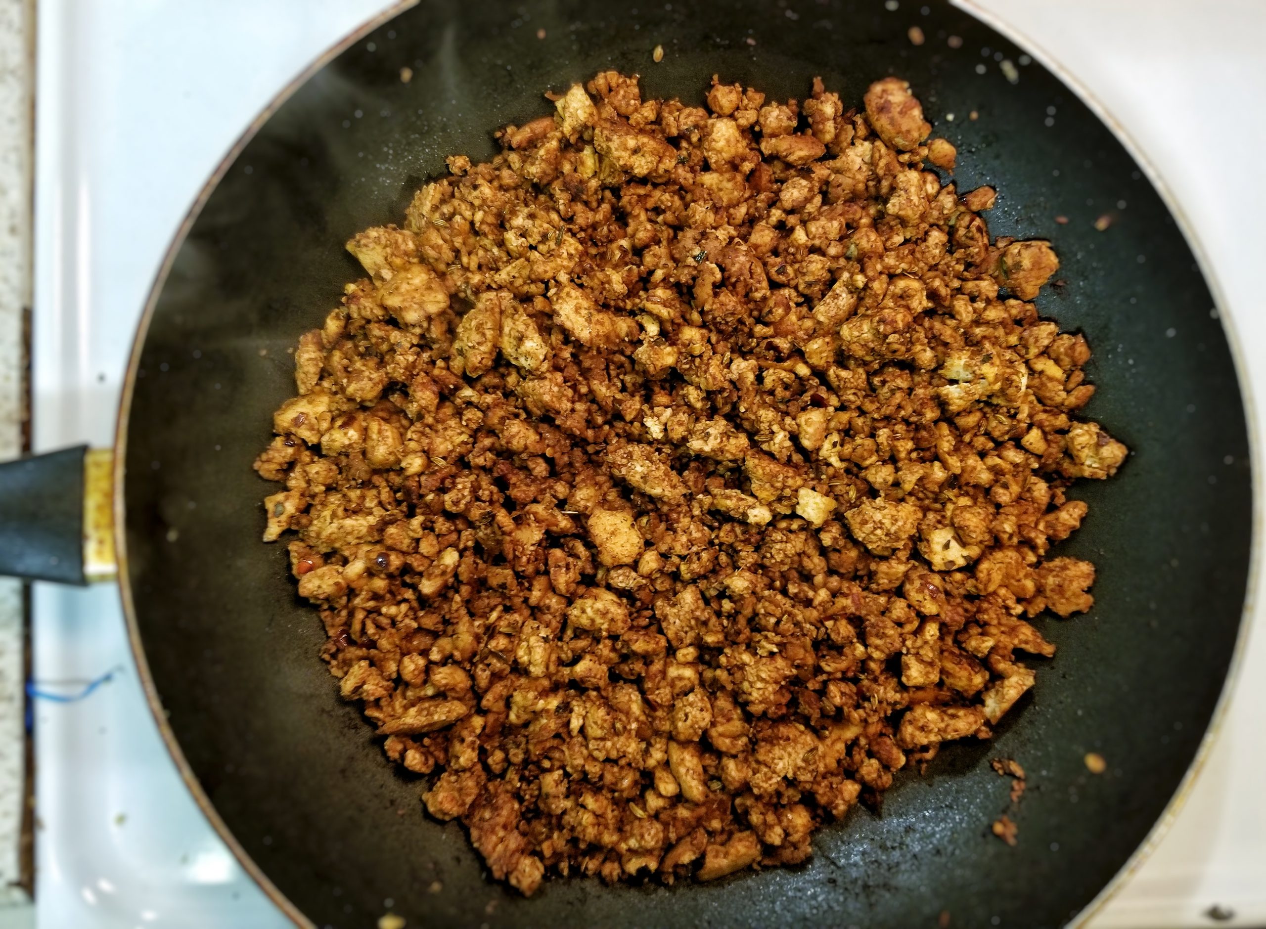 Tofu sausage crumbles cookin in a skillet. 