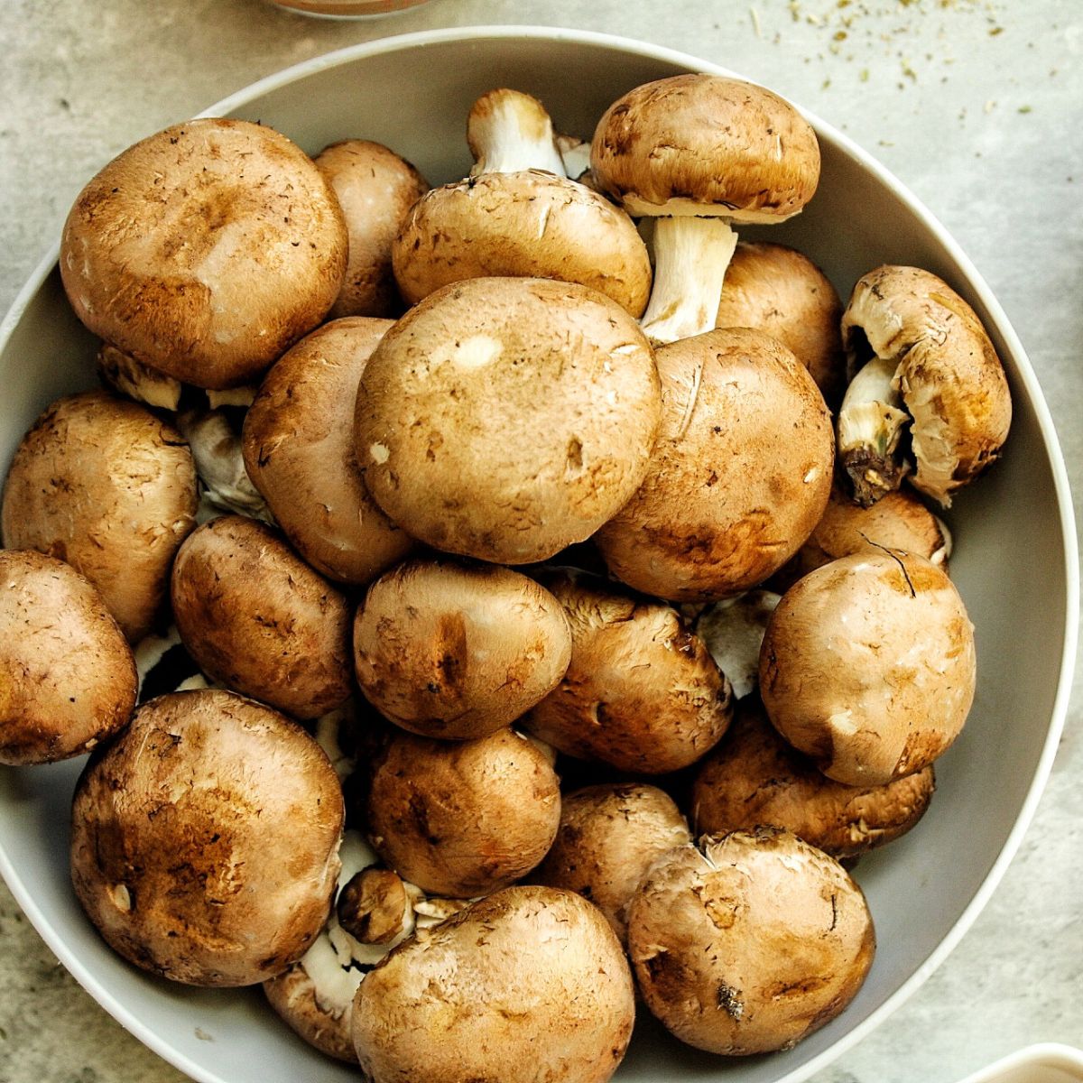 Large gray bowl of whole baby bella mushrooms.