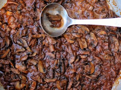 Braised mushrooms in a large, deep pan.