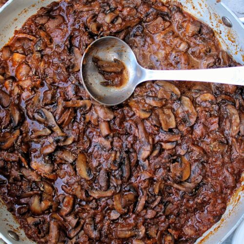 Braised mushrooms in a large, deep pan.