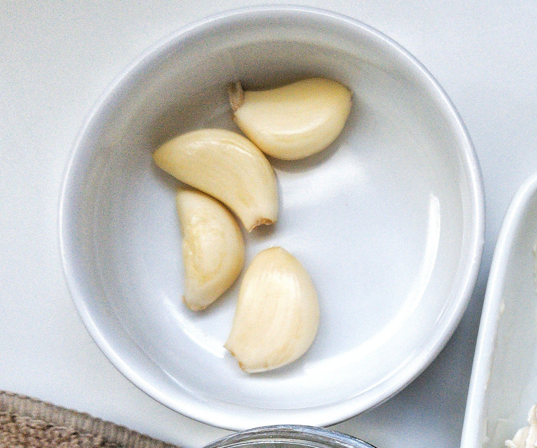 Small white bowl with garlic cloves