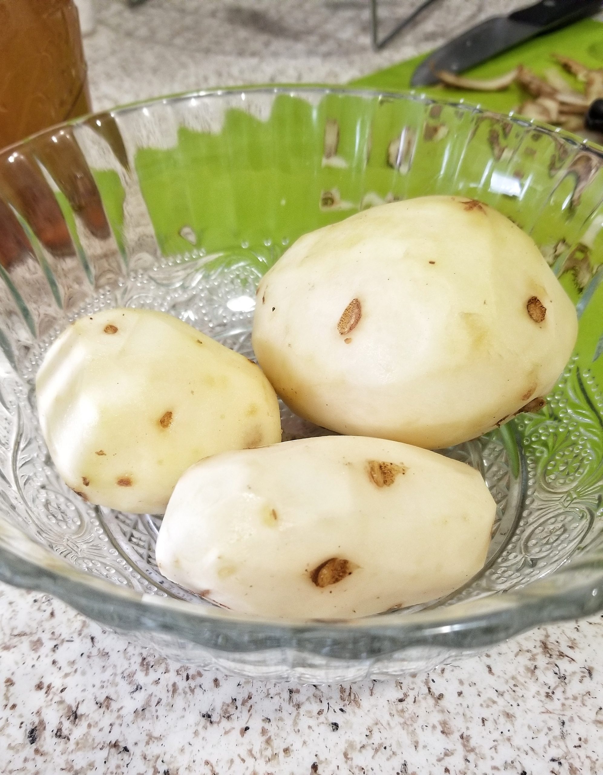 Three peeled russet potatoes in a bowl 