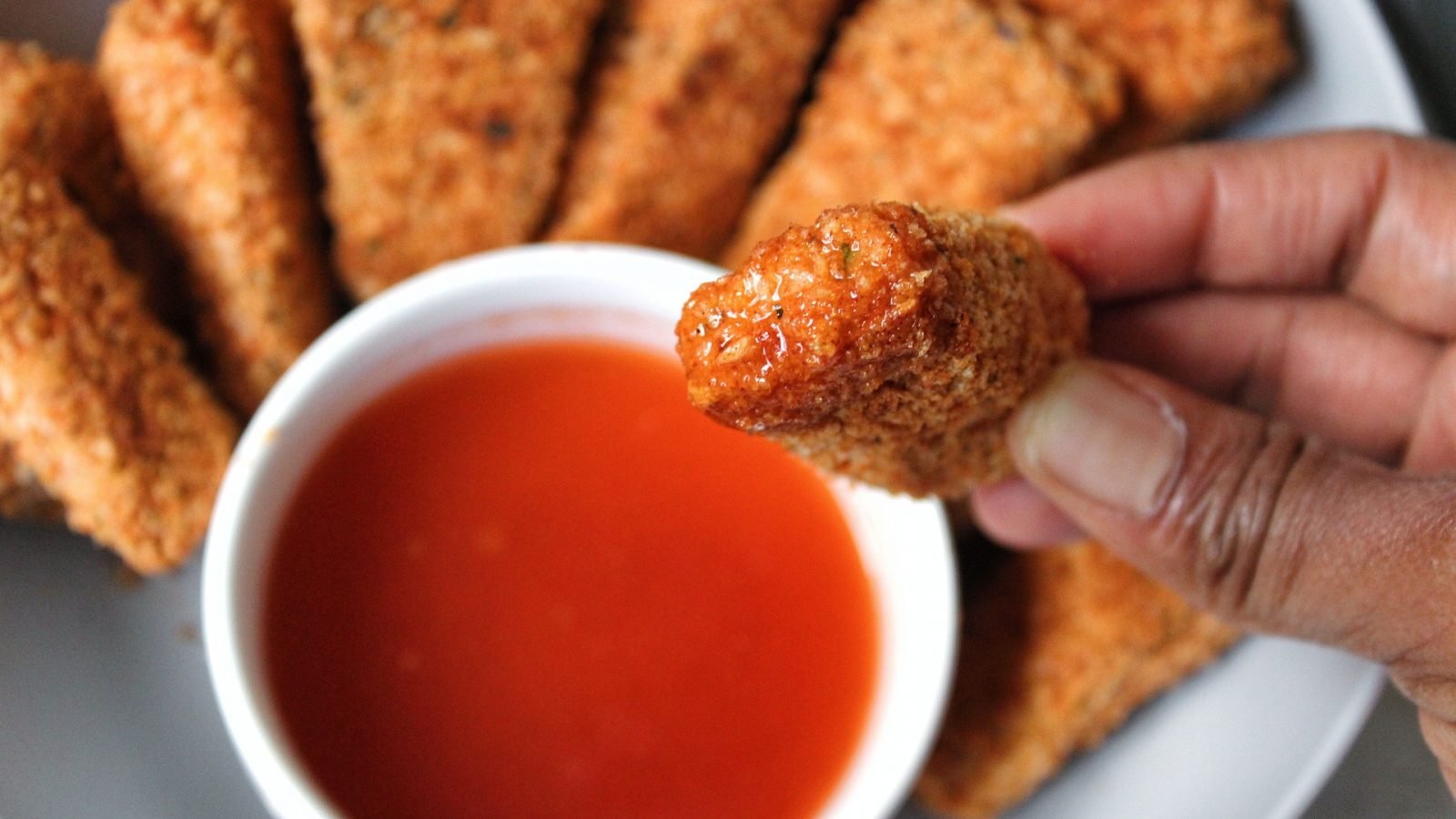 Close up extra crispy nuggets with a honey hot sauce.