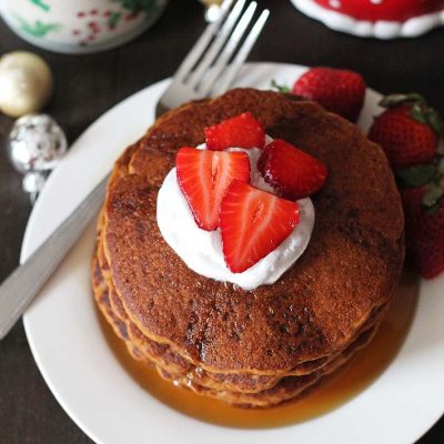Stack of gingerbread pancakes topped with sliced strawberries