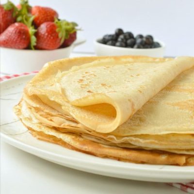 Folded crepes with a side of fruit