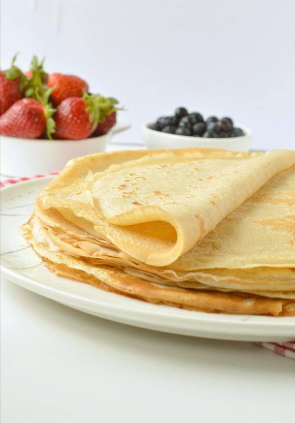 Folded crepes with a side of fruit