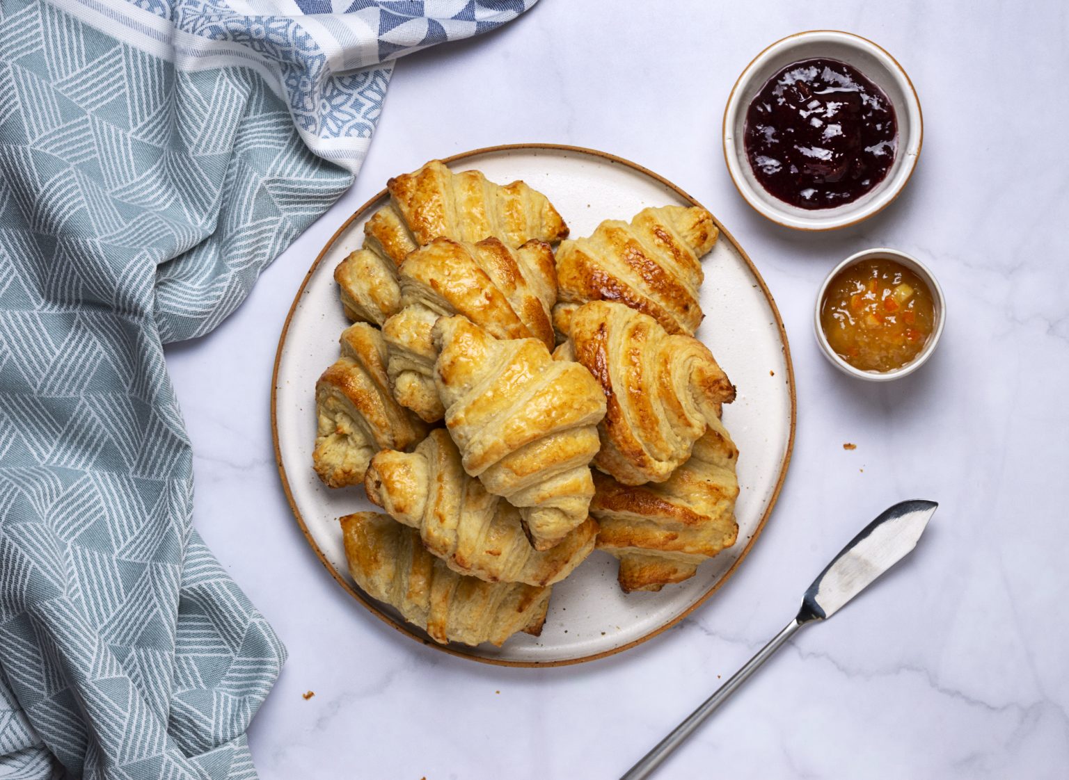 A pile of vegan croissants with a side of jam