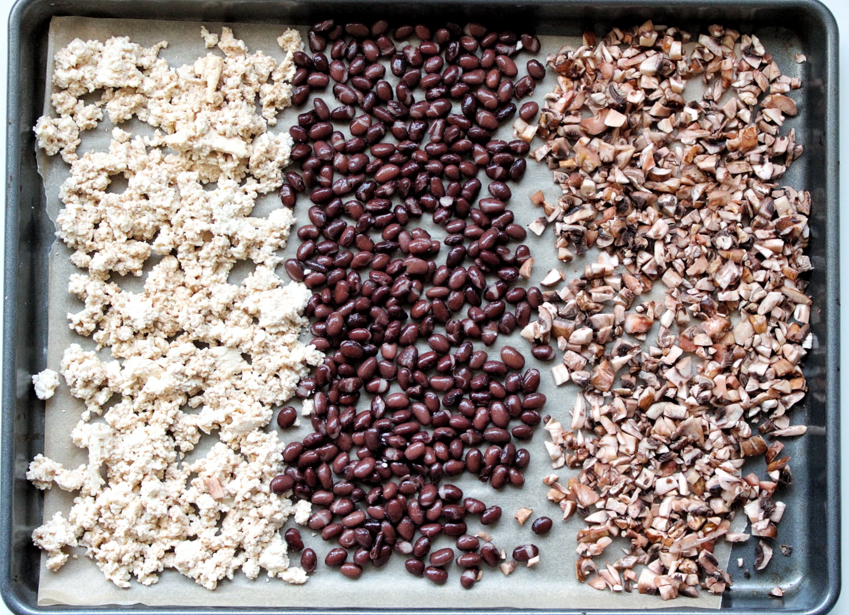 Baking tray lined with parchment paper with tofu, beans, and mushroom