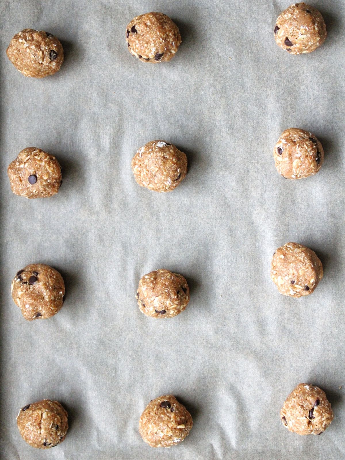Oat cookie dough balls on parchment paper. 