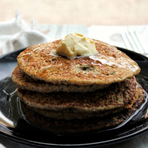 Stack of gluten-free oat bran pancakes topped with vegan butter and syrup.