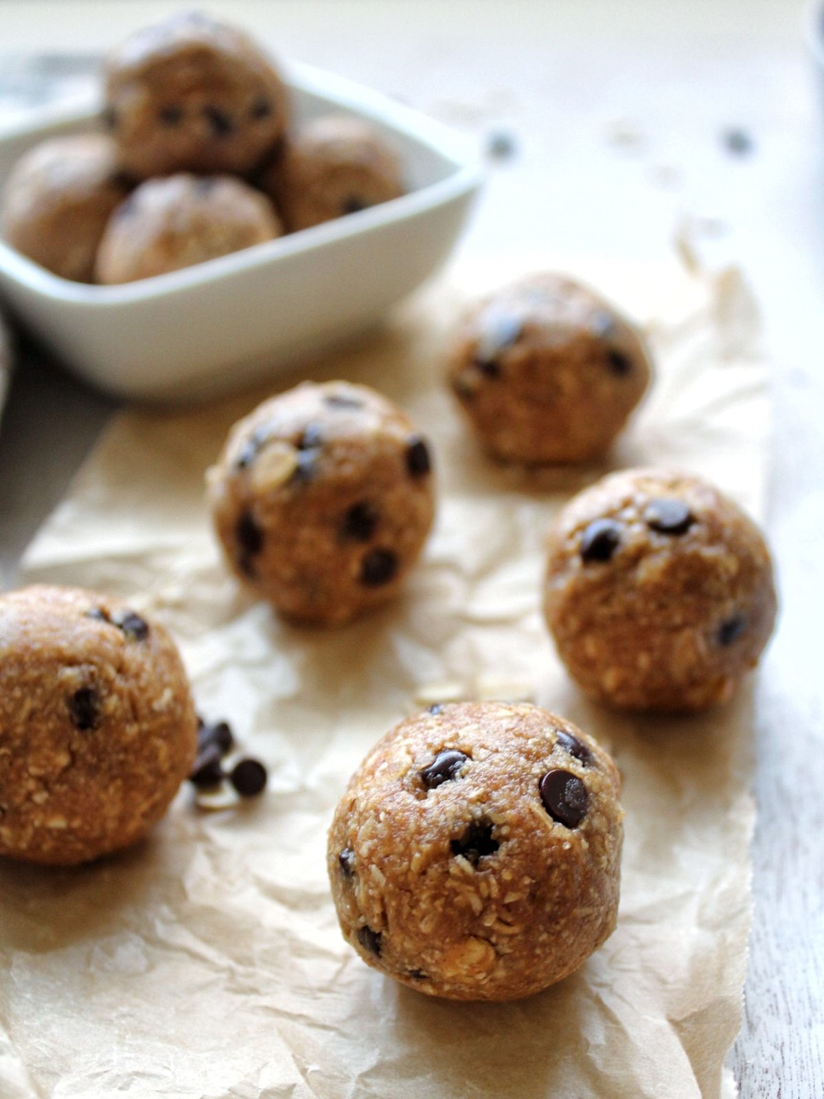 Cookie dough balls on parchment paper and extras in glass bowl. 