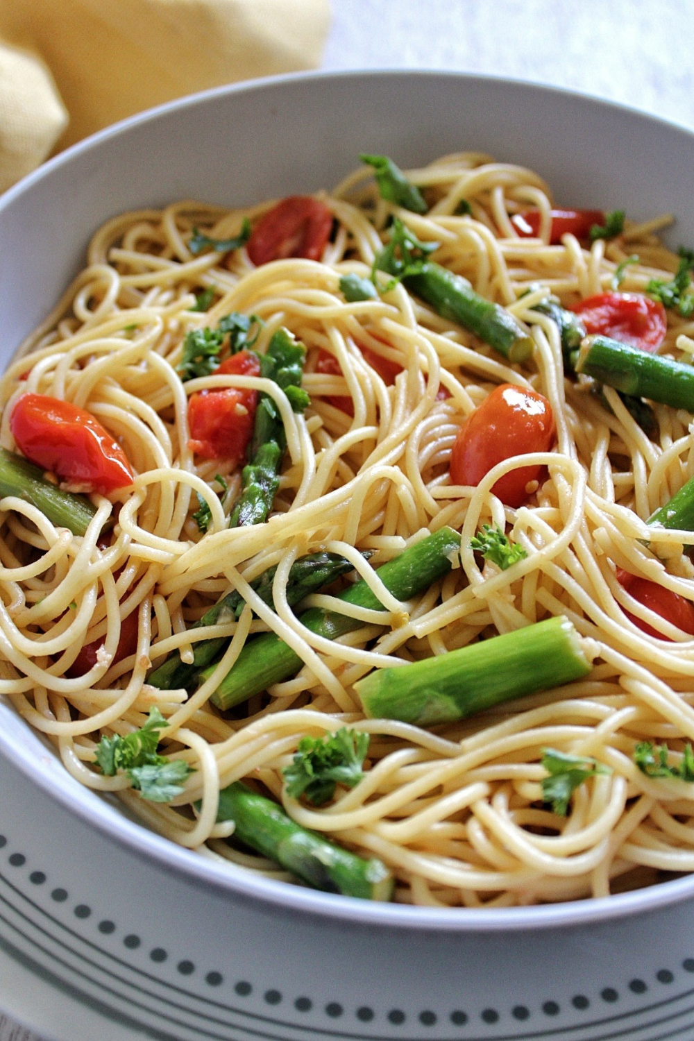 Bowl of spaghetti mixed with asparagus and tomatoes 