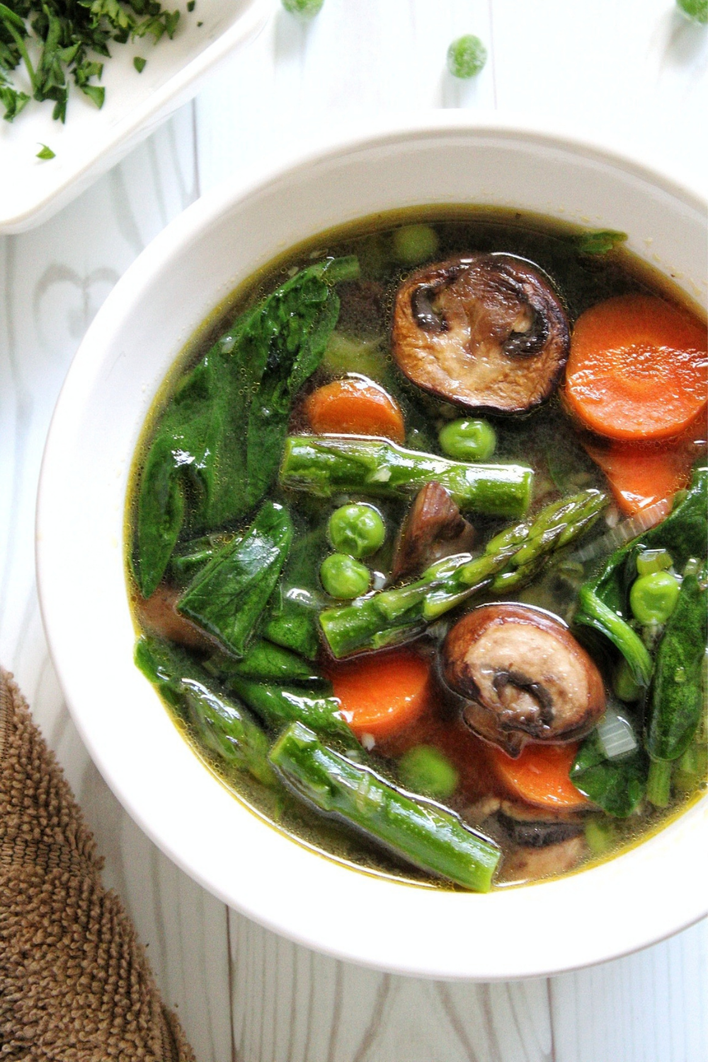 Closeup of spring soup with sliced mushrooms and carrots served in a white bowl 