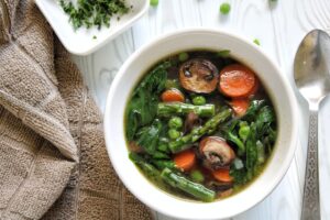 Springtime soup with mushrooms, asparagus, peas, and carrots