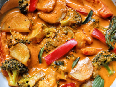 Thai-style vegetable curry in a bowl made with red bell peppers, potatoes, and broccoli.