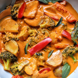 Thai-style vegetable curry in a bowl made with red bell peppers, potatoes, and broccoli.