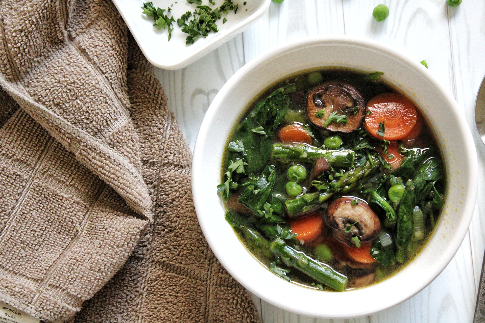 Spring soup in a bowl with a side bowl of chopped cilantro 