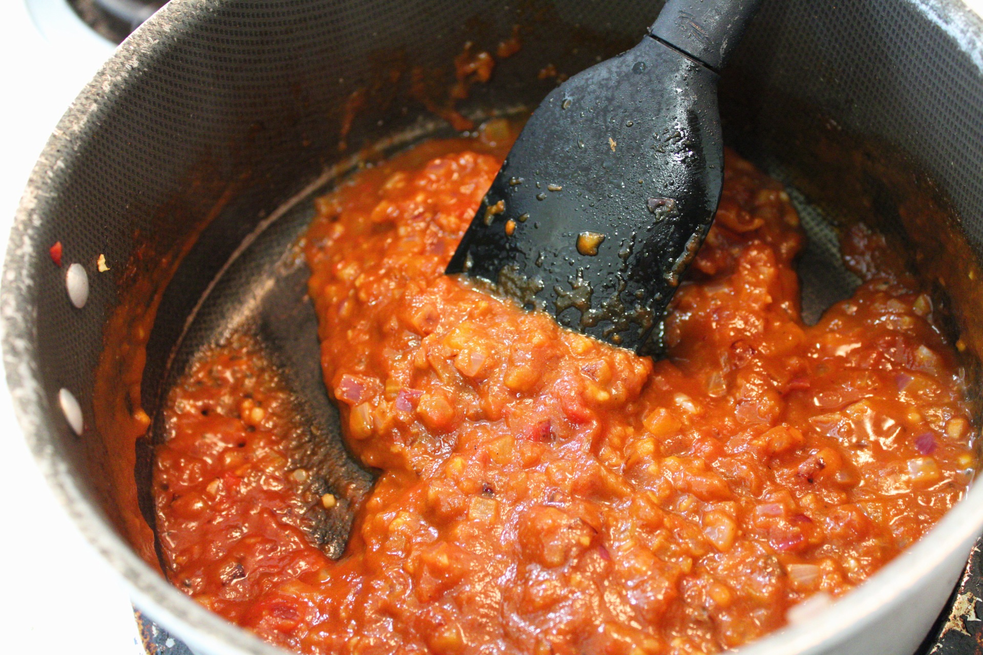 Onions, garlic, and chipotle sauce simmering in a saucepan. 