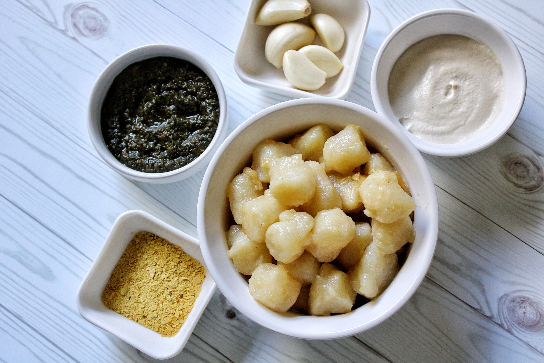 Gnocchi, cashew sauce, garlic, pesto, and nutritional yeast in small bowls 