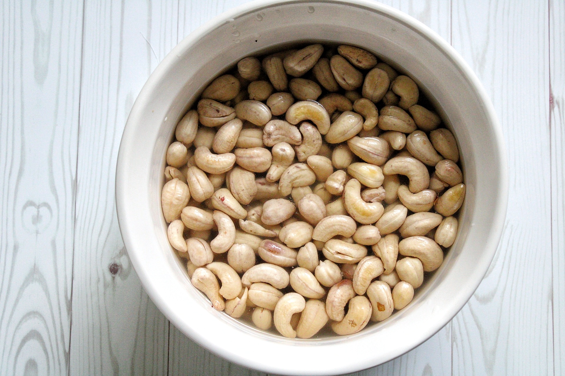 Raw cashews soaked in water in a small bowl. 