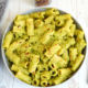 Rigatoni pasta in a creamy avocado sauce in a gray bowl. Topped with chili flakes.