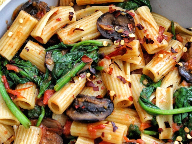 One-pot rigatoni pasta in a bowl with mushrooms, spinach, red chili flakes.