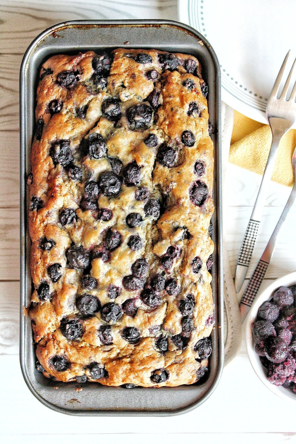 Loaf of banana bread with blueberries with aside of frozen blueberries