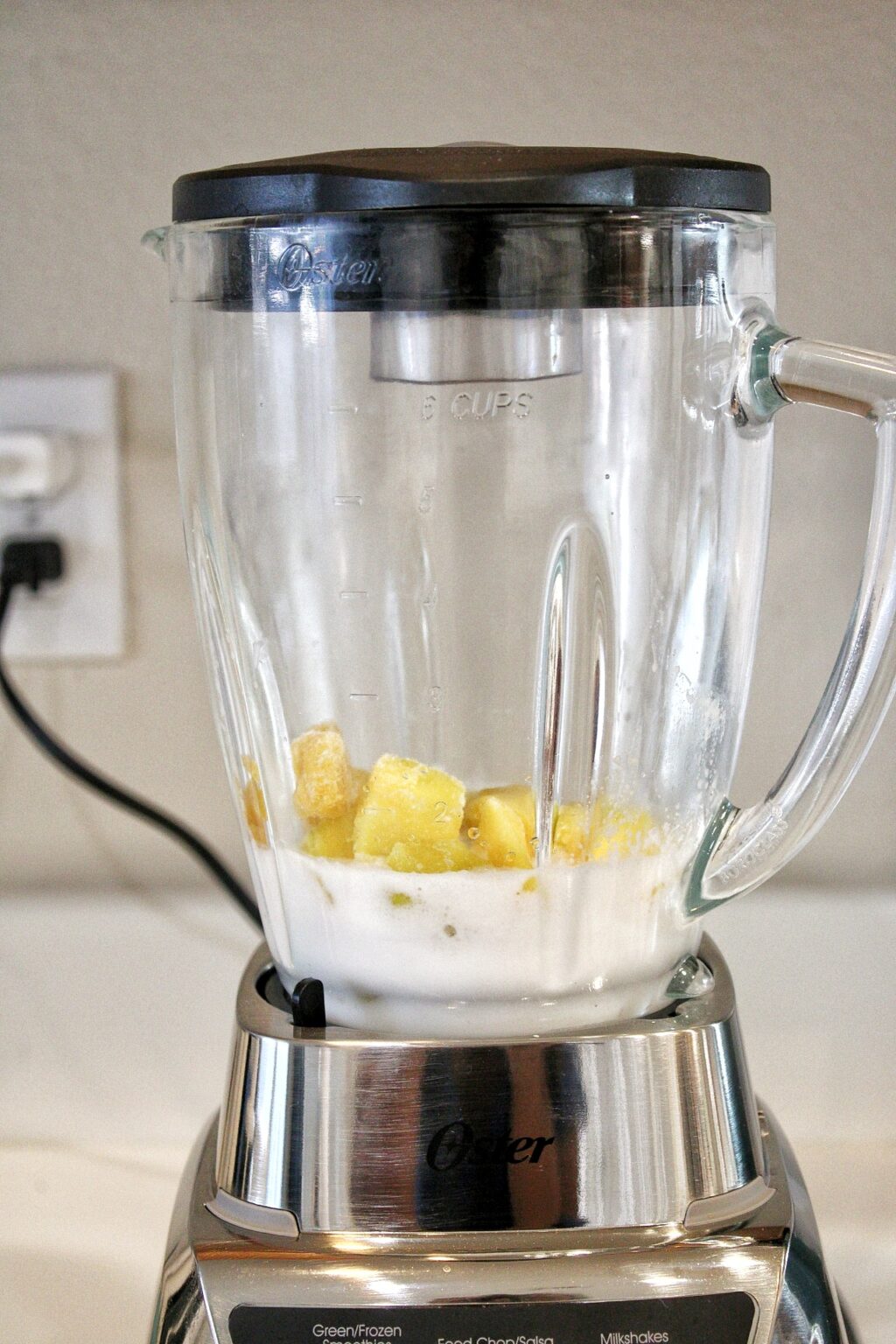 Frozen mango, coconut milk, and water in a blender. 