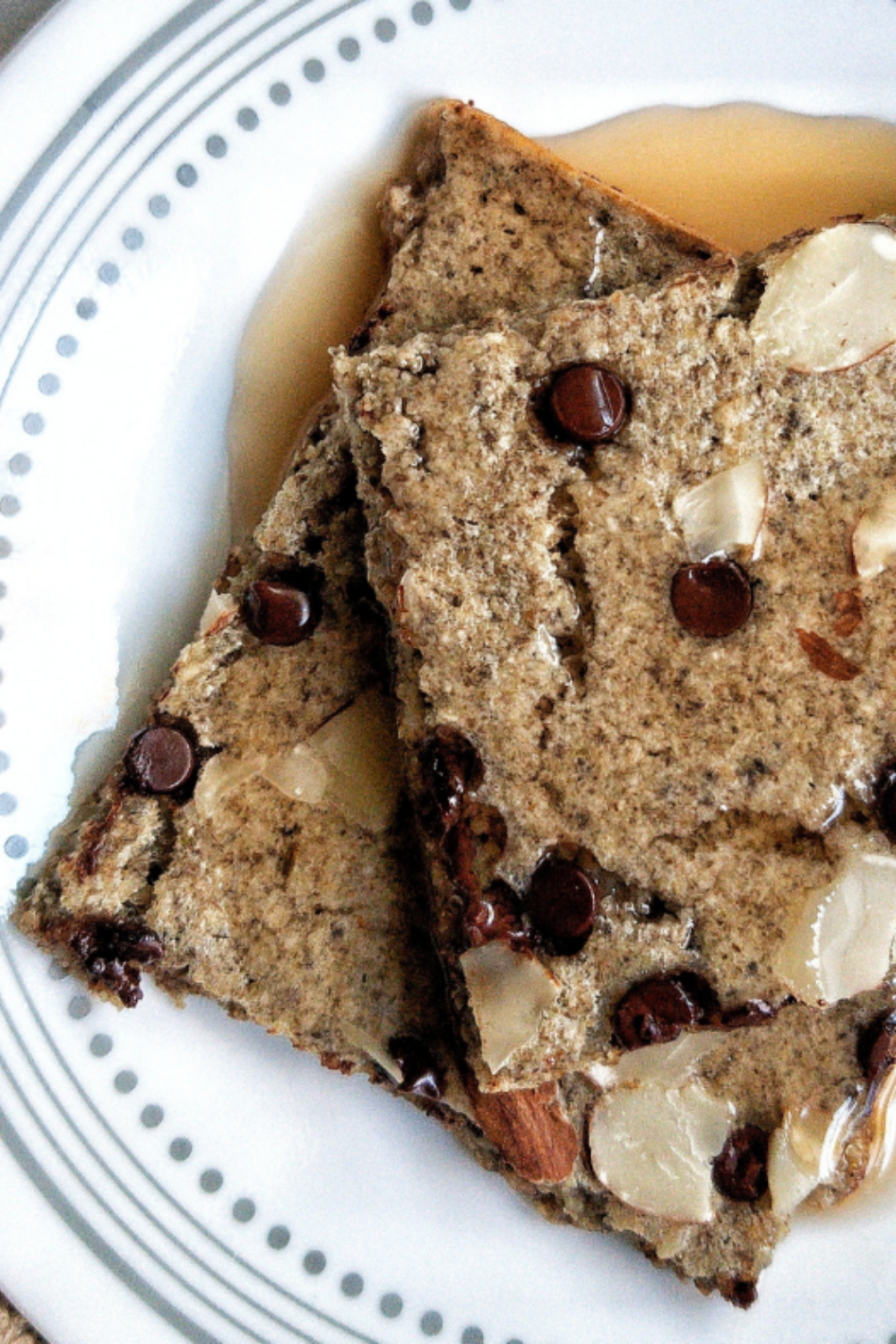 Close-up of sheet pancake squares with chocolate chips, sliced almonds, and syrup