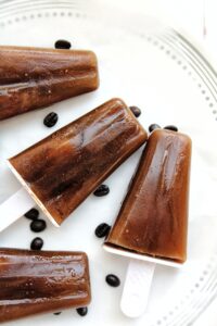 Iced coffee popsicle on a plate with coffee beans