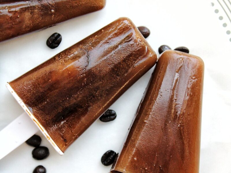 Iced coffee popsicle on a plate with coffee beans