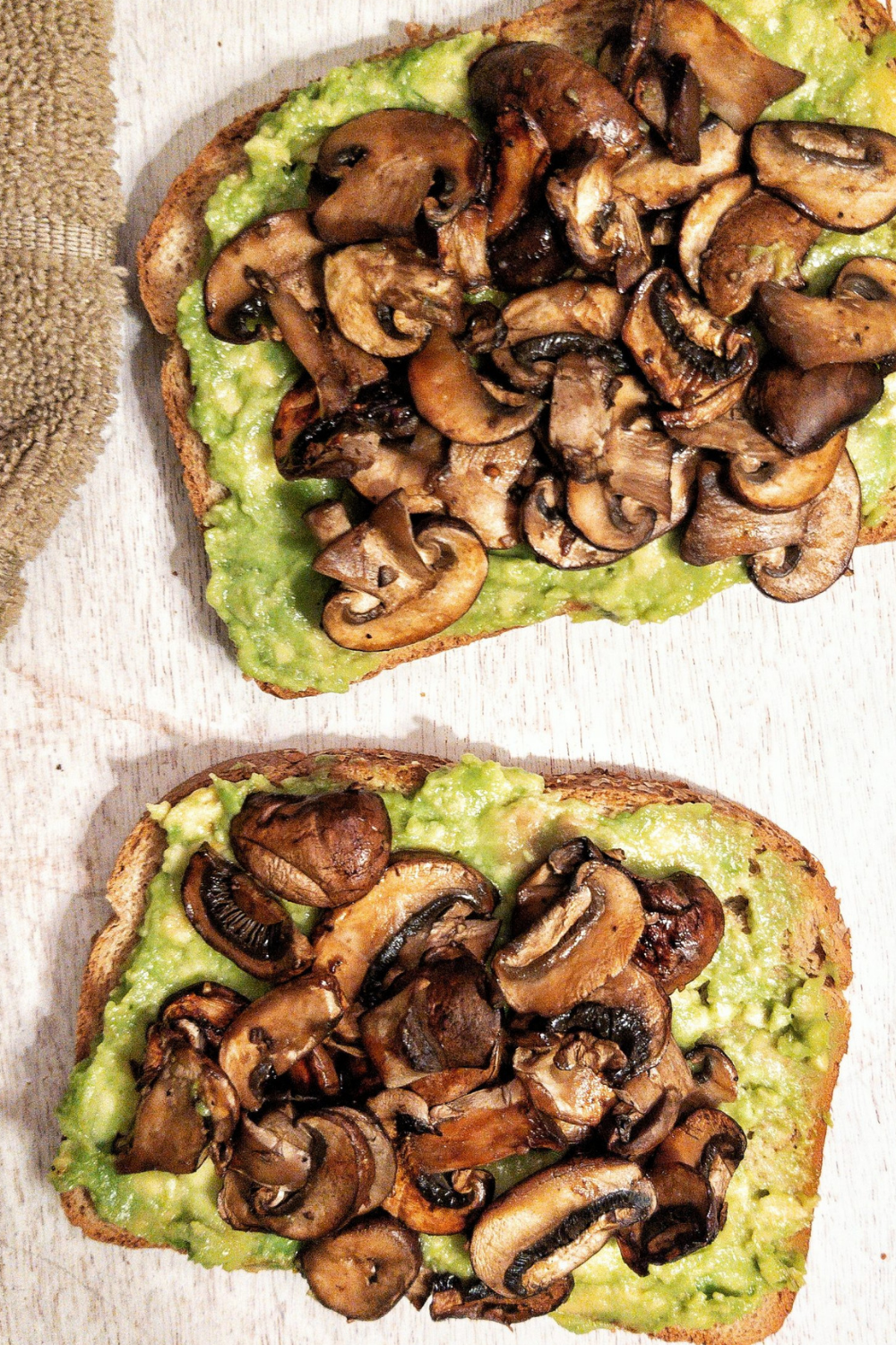 Sliced, cooked mushrooms on avocado toast. 