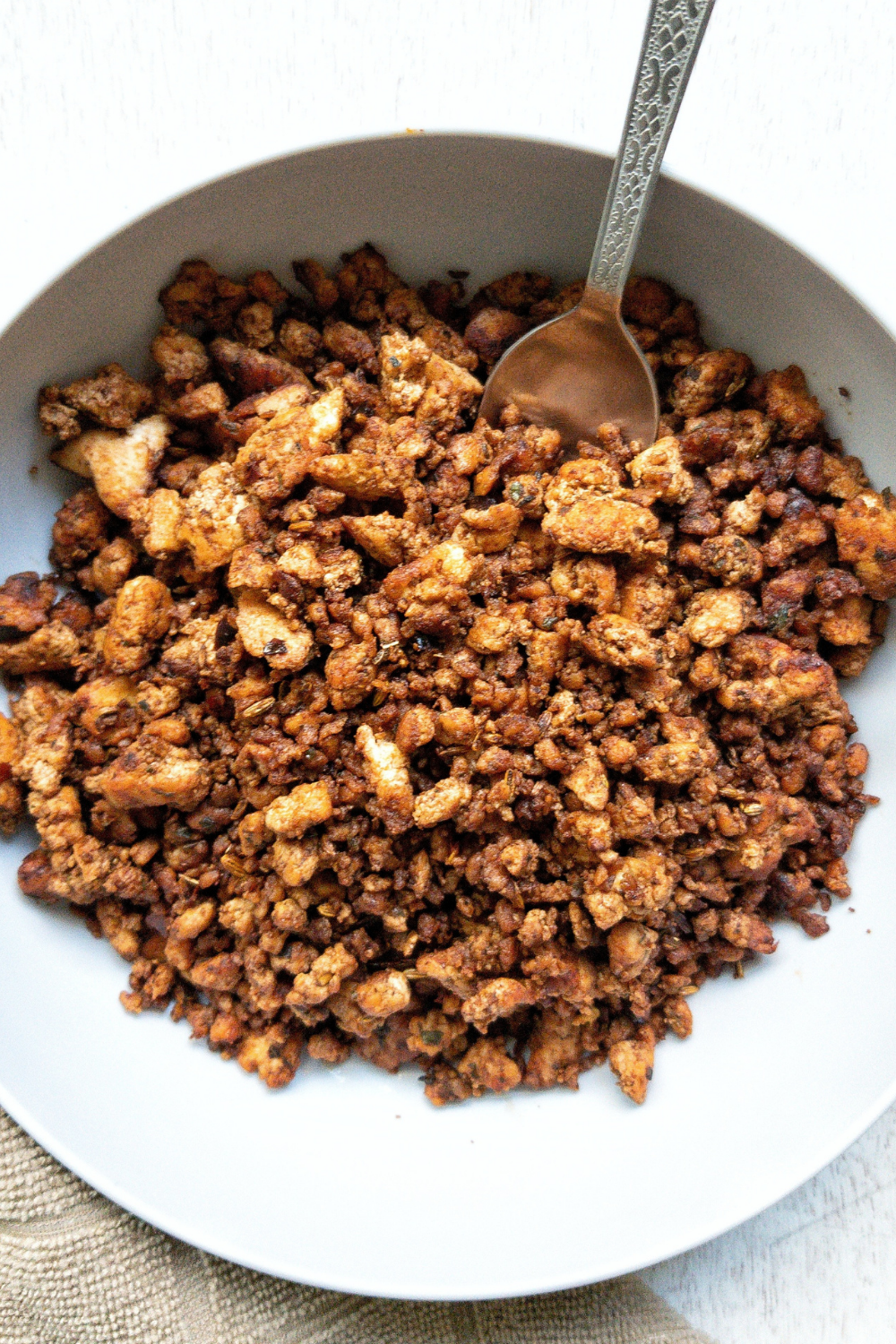 Tofu sausage crumbles in a gray bowl with a spoon