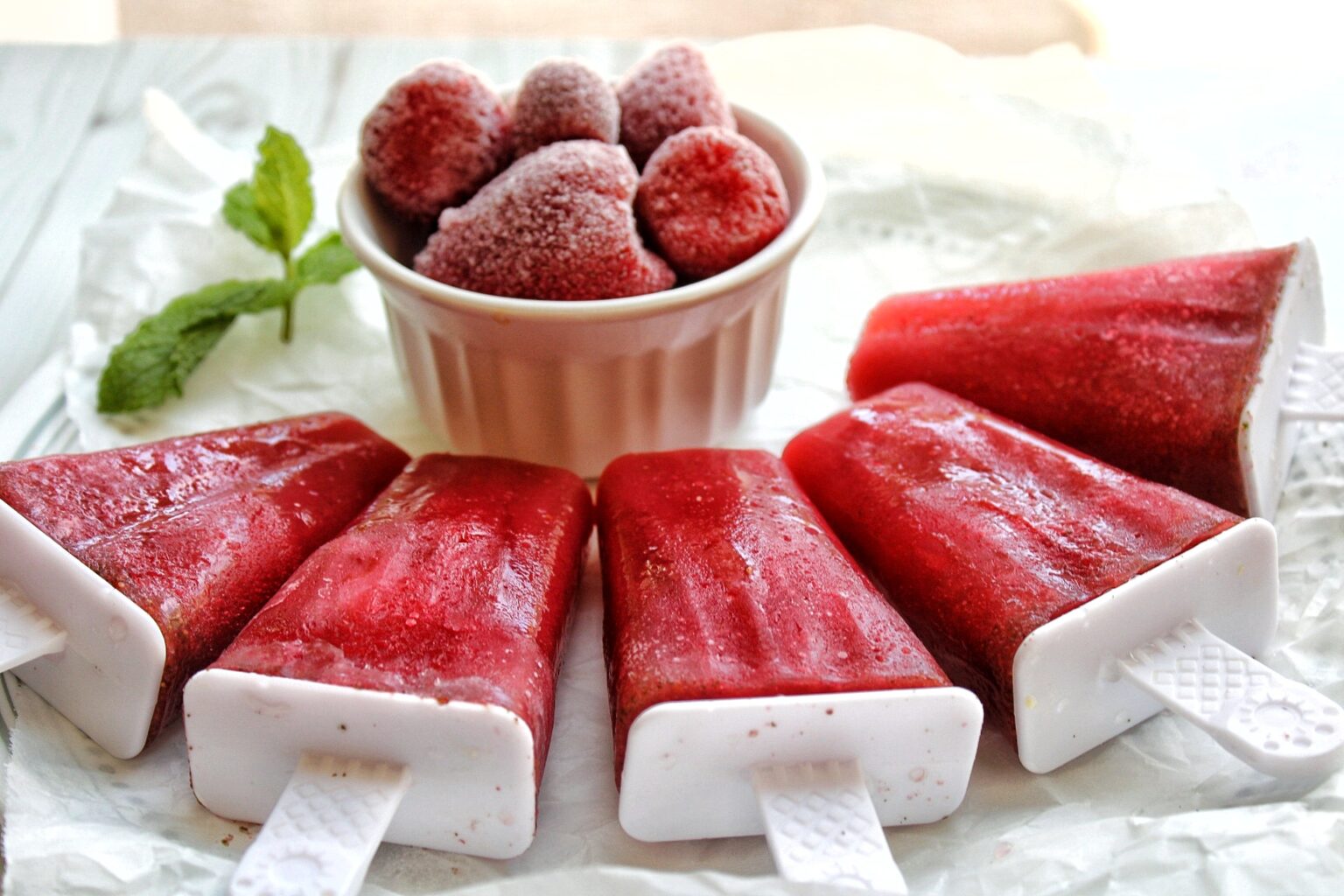 Strawberry mint popsicles served with frozen strawberries. 