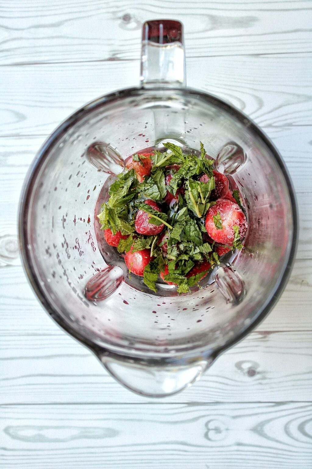 Frozen strawberries and fresh mint in a blender. 